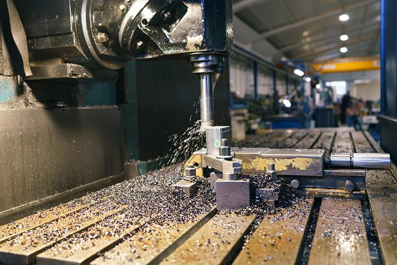 Fresadora mecanizando una pieza de metal entre virutas, en una nave industrial